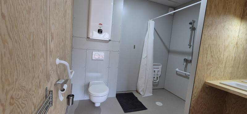 Salle d'eau spacieuse disposant d'une douche adaptée et d'équipements PMR